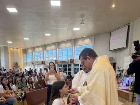 A catequisanda Laura Calderan recebendo pela primeira vez a Eucaristia