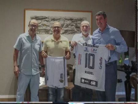 Riedel recebeu a camisa do Galo das mãos de Carlos Alberto Rezende, o professor Carlão, e do empresário José Thomaz Filho, e do diretor geral do Campo Grande News, jornalista Lucimar Couto.